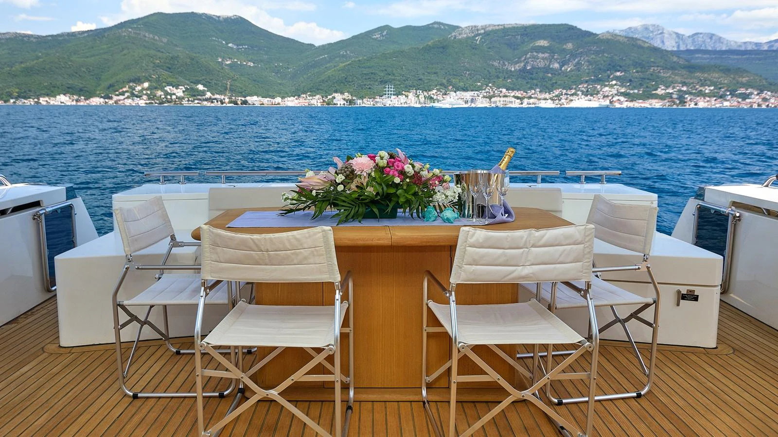 The aft deck features a stylish dining area with scenic views of the water and mountains. aboard GANS Yacht for Sale