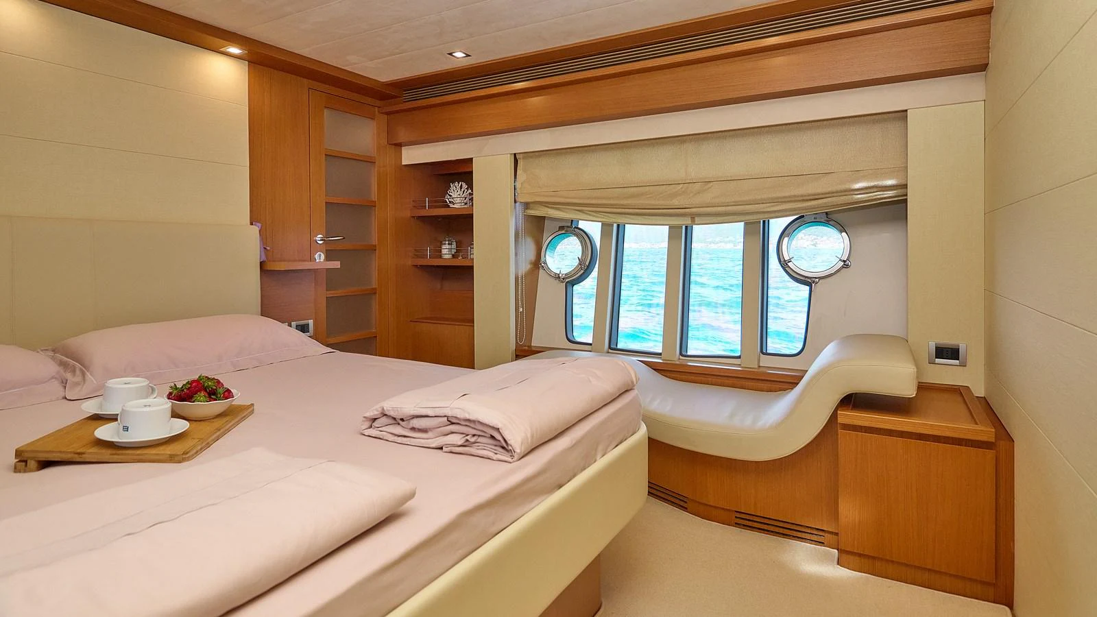 A cozy stateroom with a comfortable bed and a view of the sea through porthole windows. aboard GANS Yacht for Sale