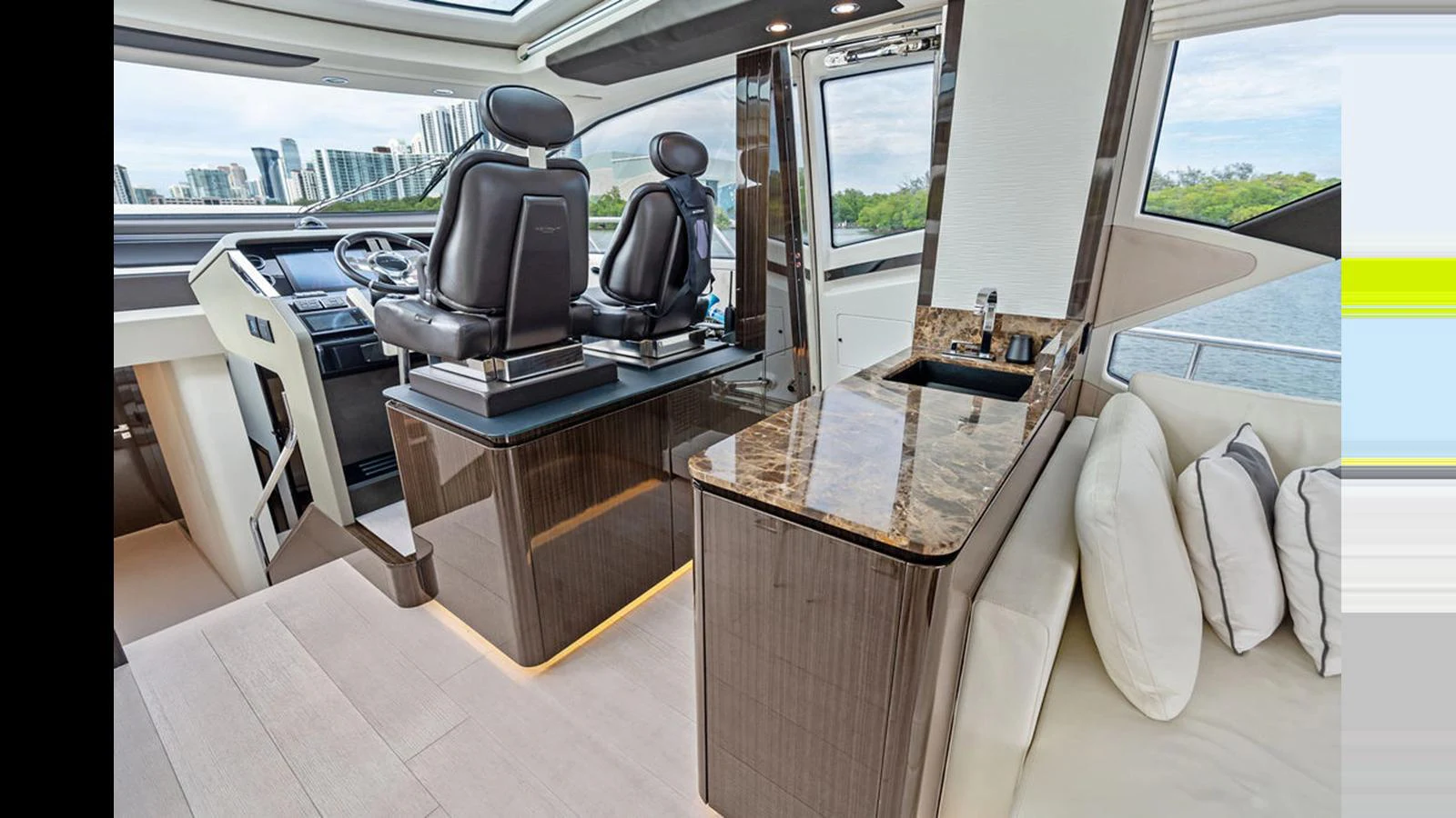 The helm area features luxurious seating and a sleek control console with a nearby sink and countertop. aboard VILLAGGIO Yacht for Sale