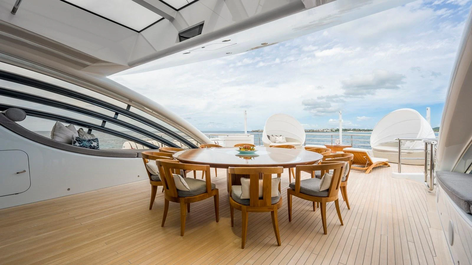 The aft deck features a spacious dining area with elegant wooden chairs and a large table, perfect for outdoor meals. aboard NENINKA Yacht for Sale