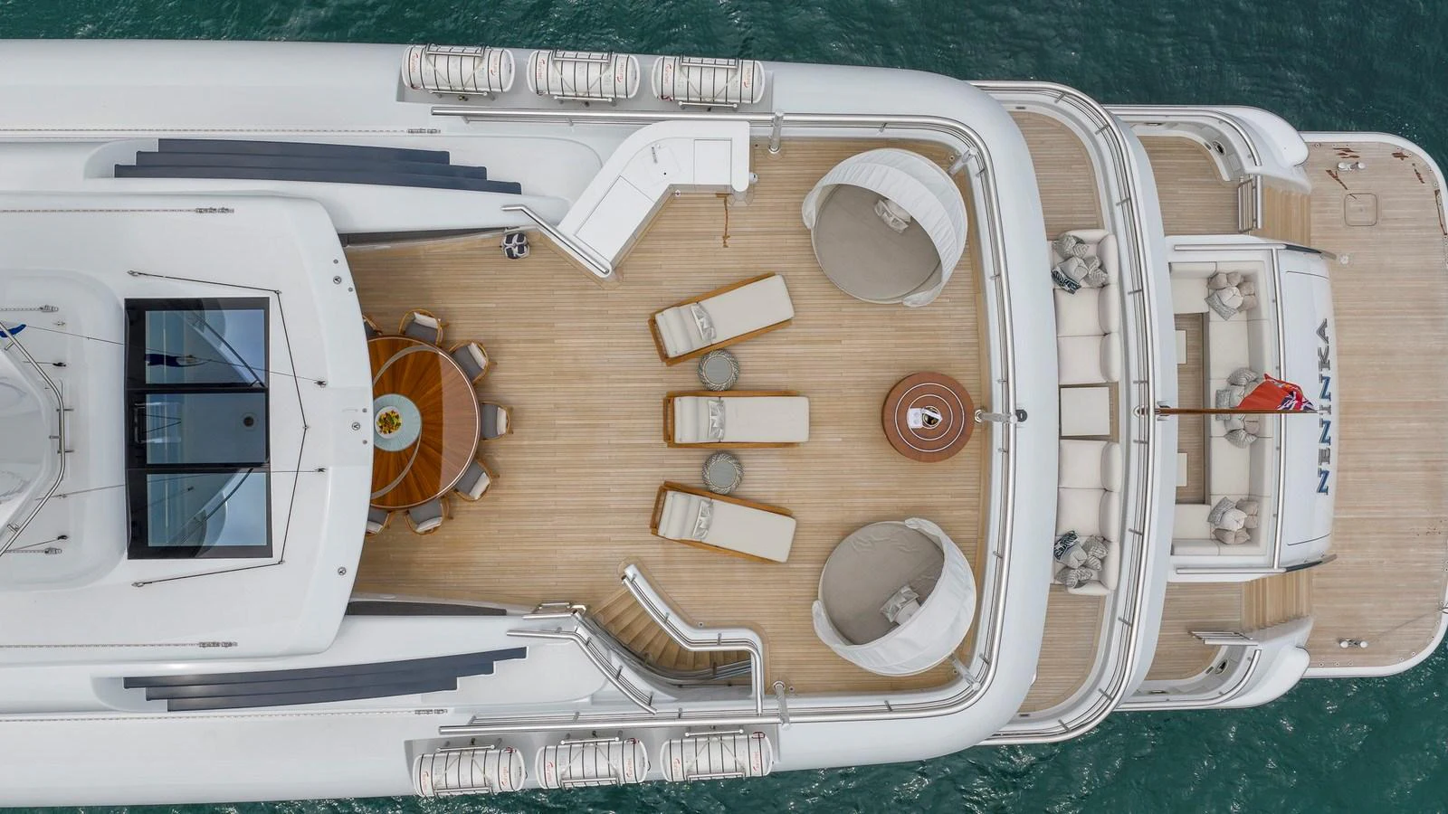 A spacious sundeck with lounge chairs and a dining area overlooking the water. aboard NENINKA Yacht for Sale