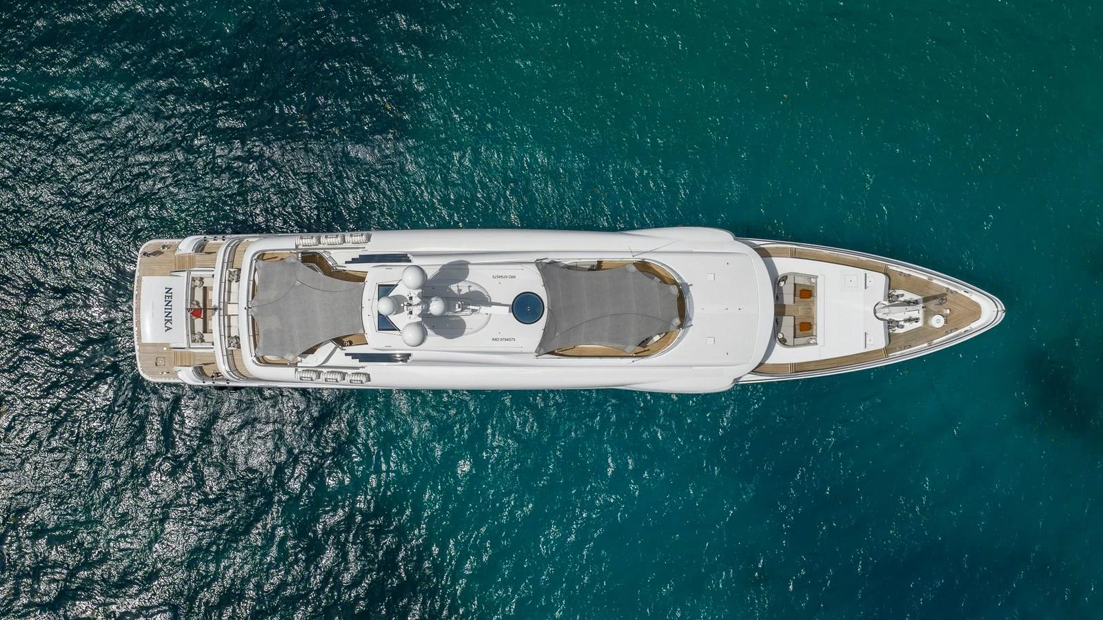 Aerial view of a sleek yacht cruising through clear blue waters. aboard NENINKA Yacht for Sale