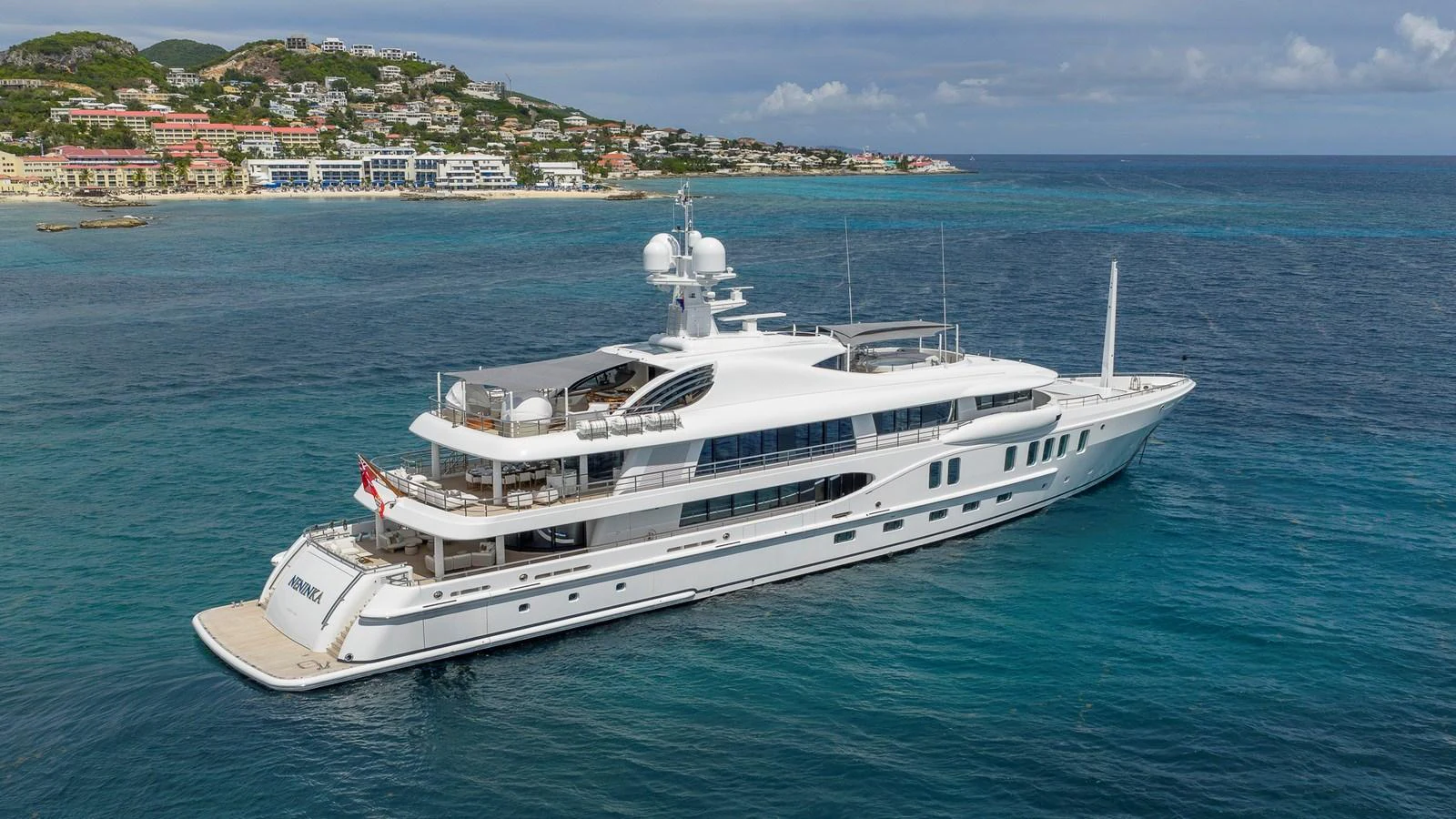 A sleek white yacht cruises along a picturesque coastline with clear blue waters. aboard NENINKA Yacht for Sale