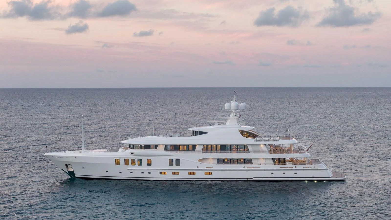 A luxurious yacht cruises serenely on calm waters under a pastel sunset sky. aboard NENINKA Yacht for Sale
