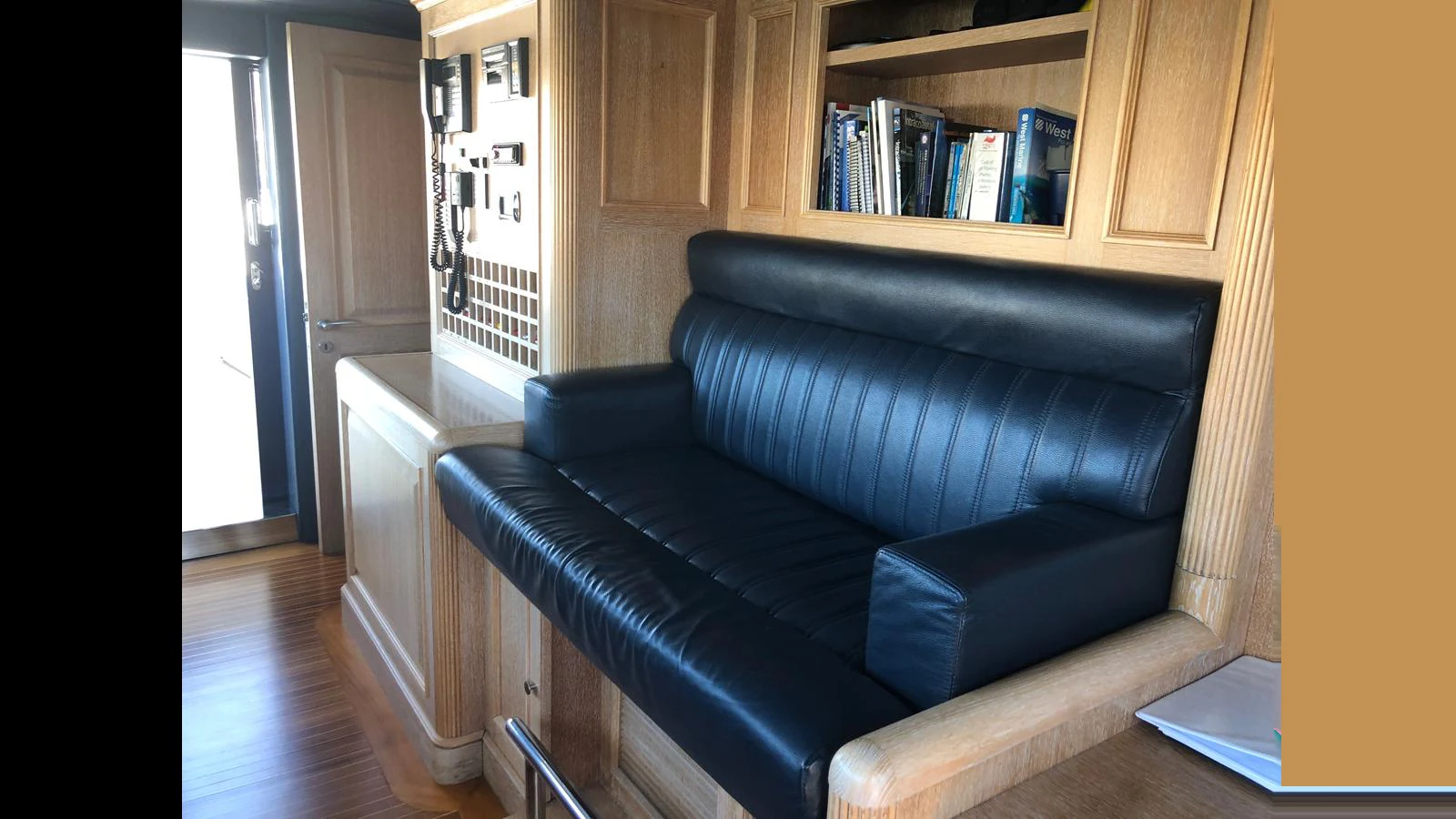 The image showcases a comfortable seating area within the yacht's interior, featuring a black leather bench and wooden cabinetry. aboard ALBATROSS Yacht for Sale