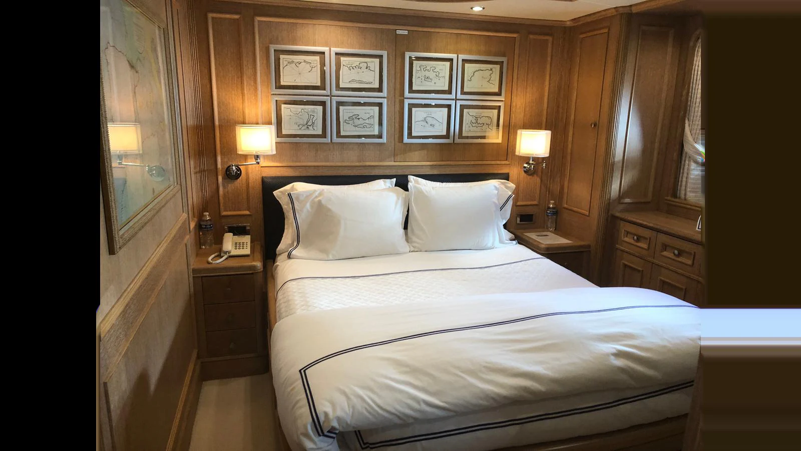 The stateroom features a luxurious bed with elegant wood paneling and framed artwork. aboard ALBATROSS Yacht for Sale
