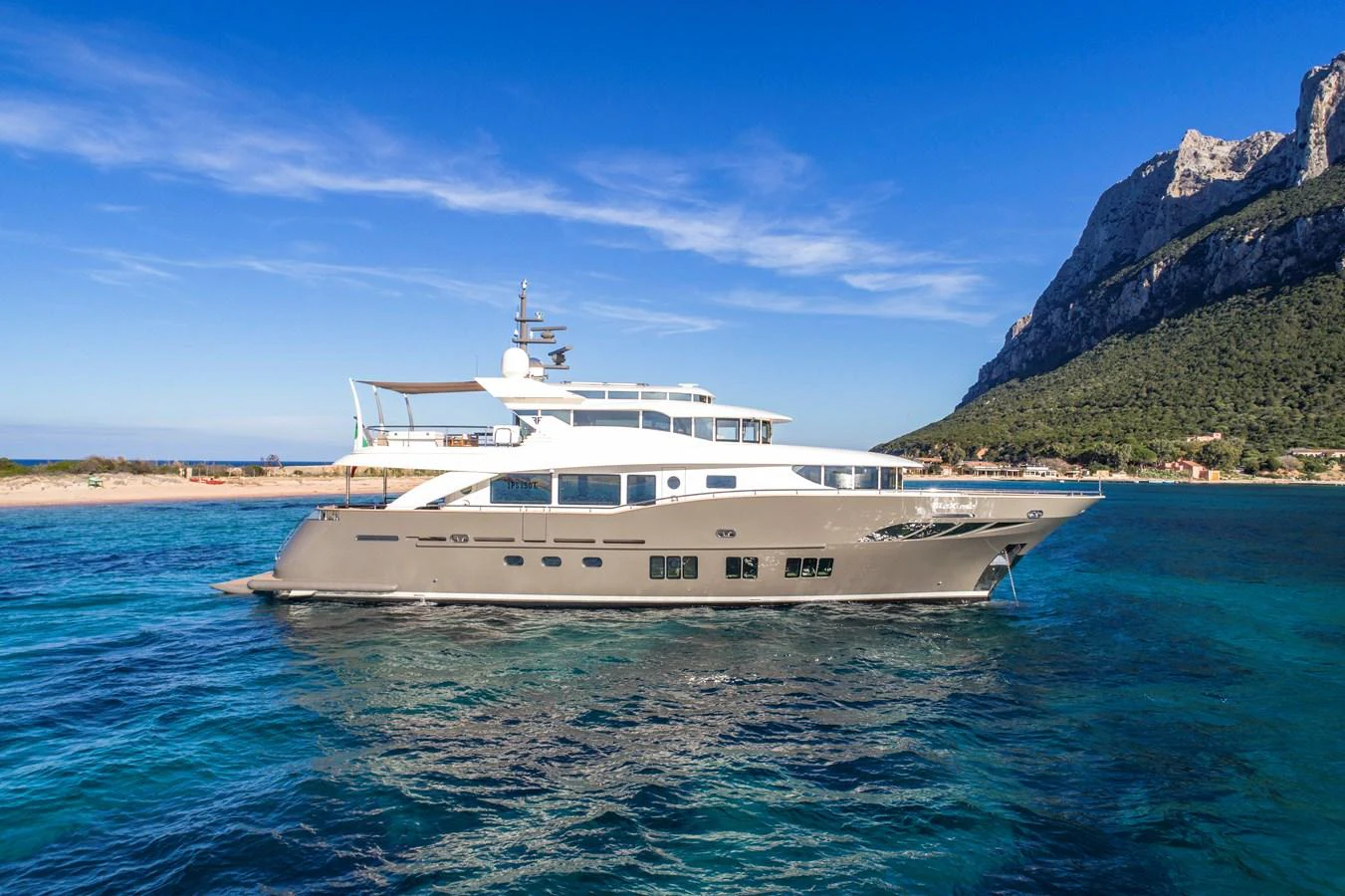 A sleek yacht cruises through clear blue waters with a stunning coastal backdrop. aboard MAXIMA Yacht for Sale