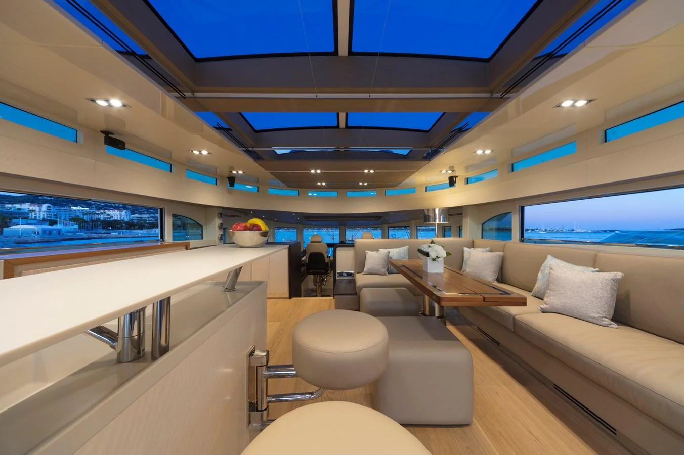 The salon features expansive windows, plush seating, and a modern, open layout with a view of the sea. aboard MAXIMA Yacht for Sale