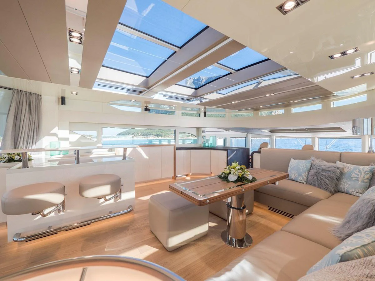 The salon features a spacious and bright interior with large windows and skylights, offering a luxurious and comfortable lounging area. aboard MAXIMA Yacht for Sale