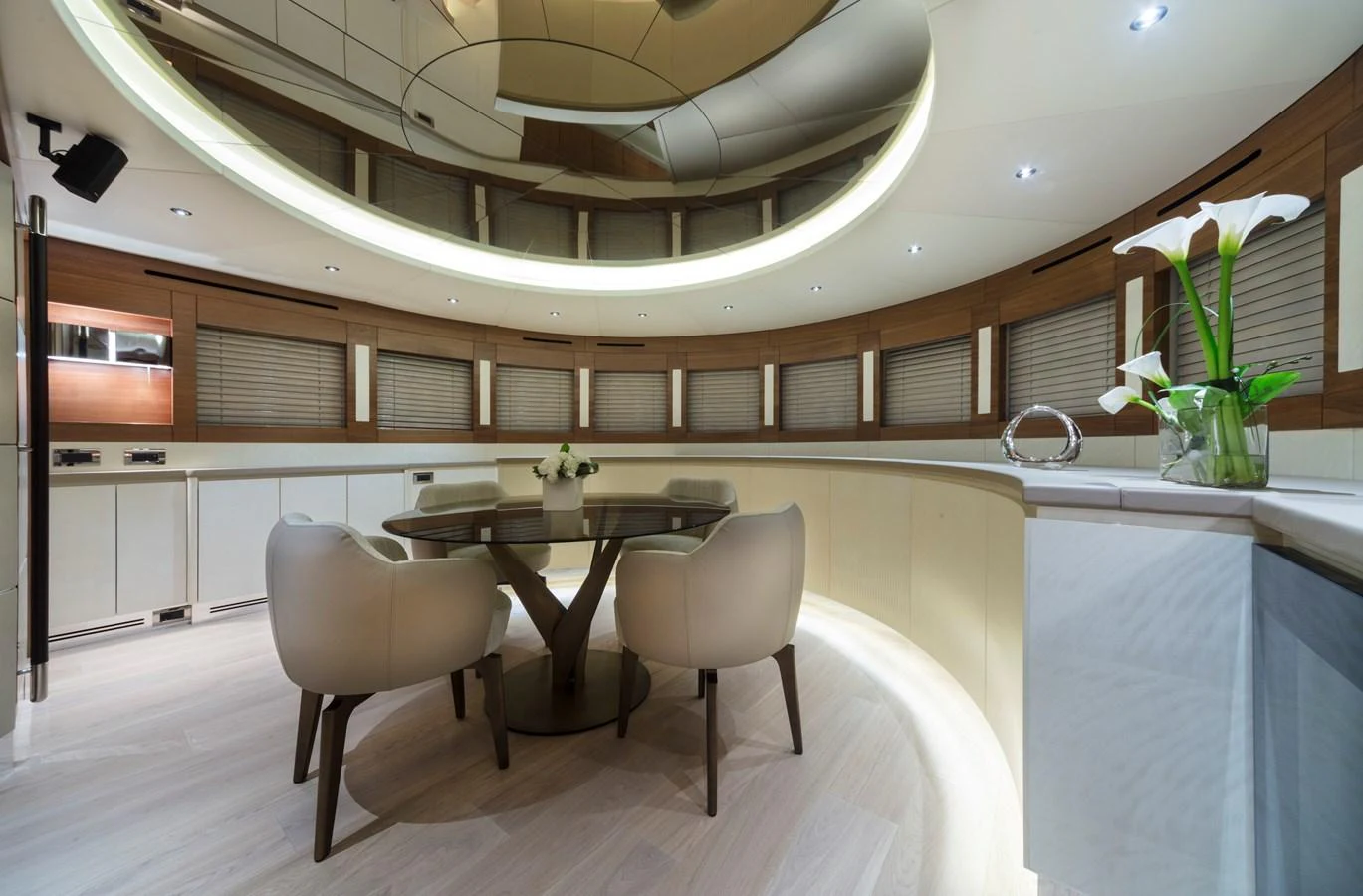 The yacht's dining area features a modern, circular table with plush seating and elegant decor. aboard MAXIMA Yacht for Sale