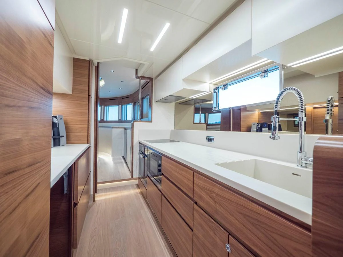 The yacht's galley features sleek wooden cabinetry and modern appliances, creating a stylish and functional space. aboard MAXIMA Yacht for Sale