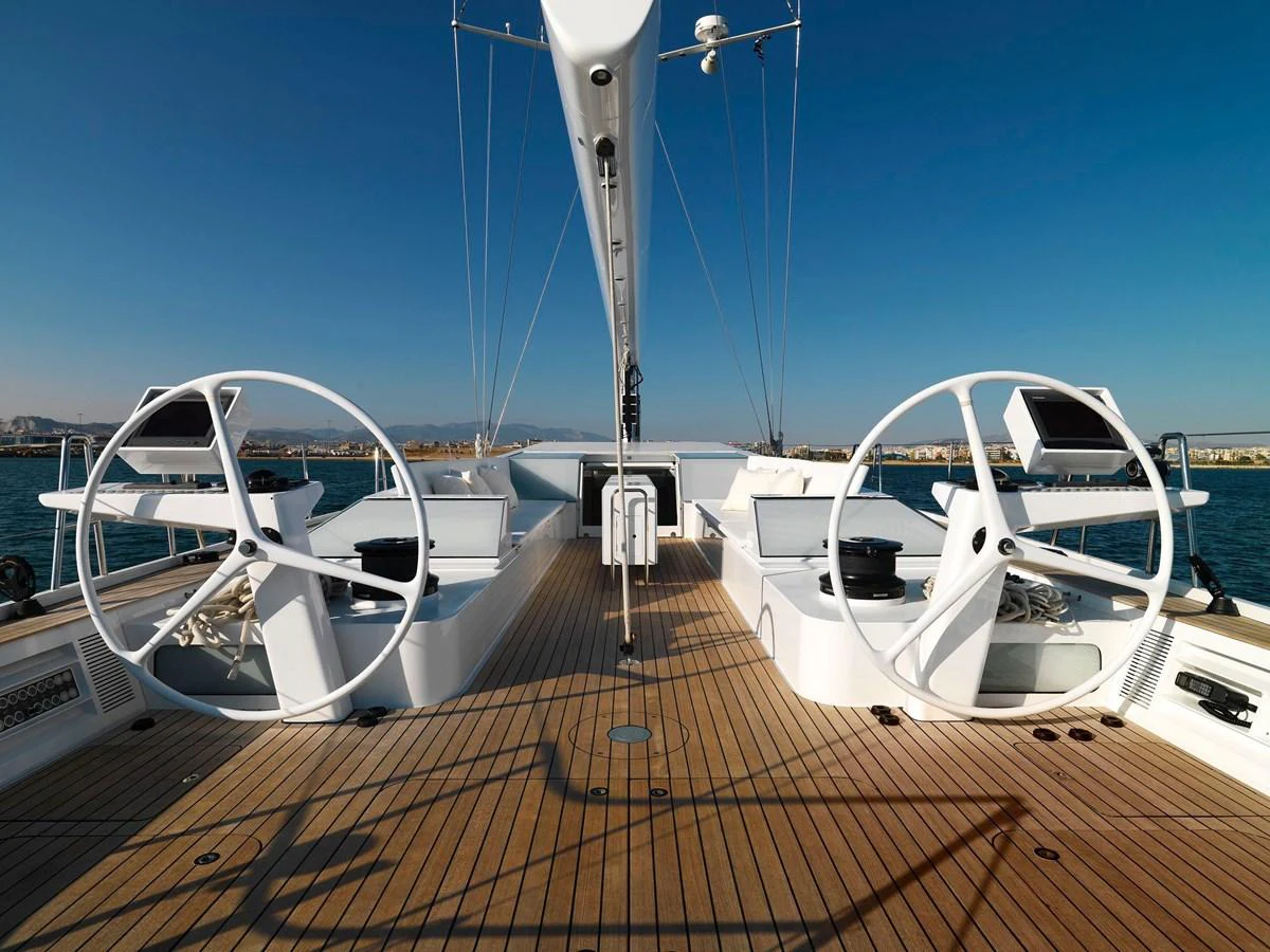 The yacht's helm features dual steering wheels and a spacious teak deck under clear skies. aboard S/Y SENTINEL Yacht for Sale