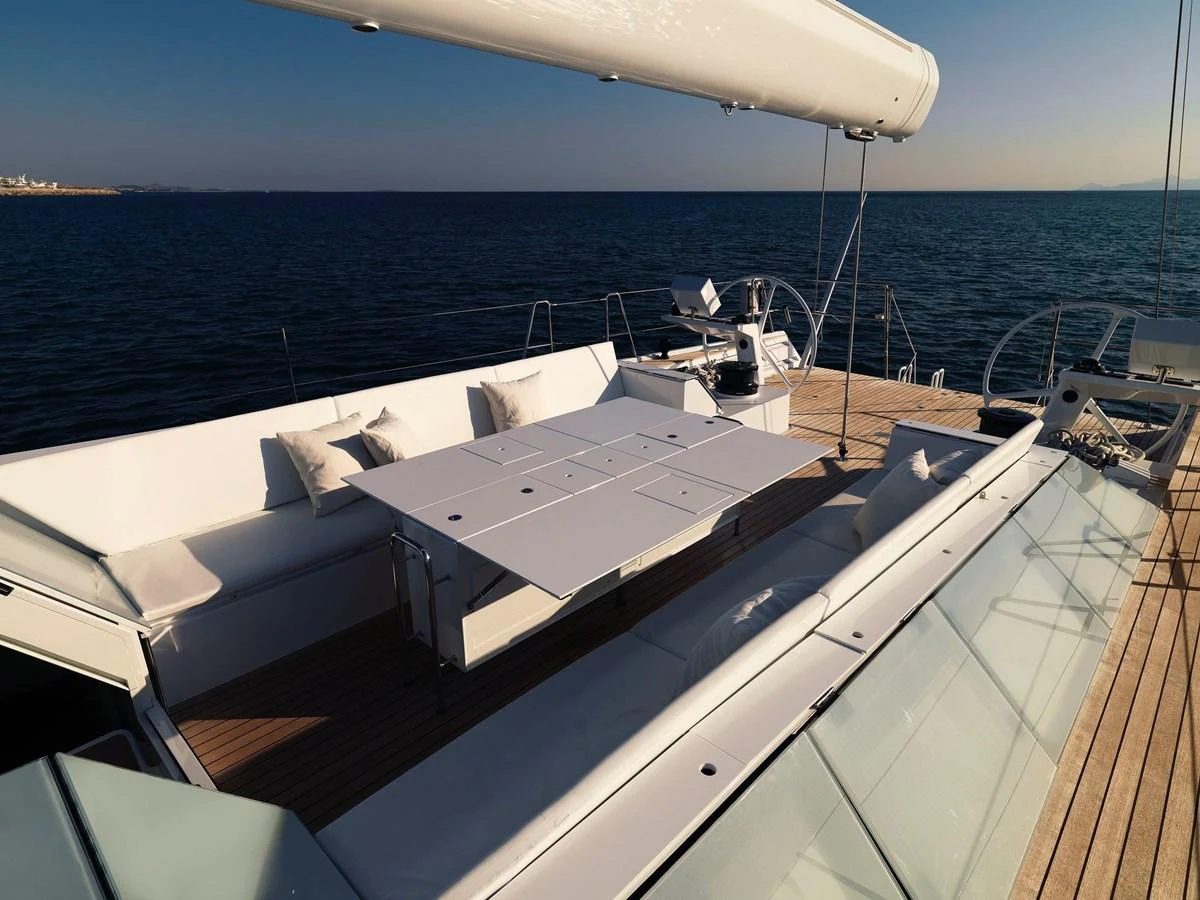 The flybridge features a spacious seating area with a dining table, perfect for enjoying meals with a view of the sea. aboard S/Y SENTINEL Yacht for Sale