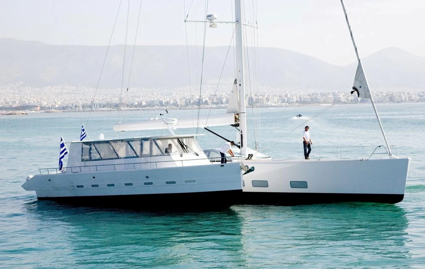 A sleek and modern yacht sails gracefully on calm waters with scenic mountains in the background. aboard S/Y SENTINEL Yacht for Sale