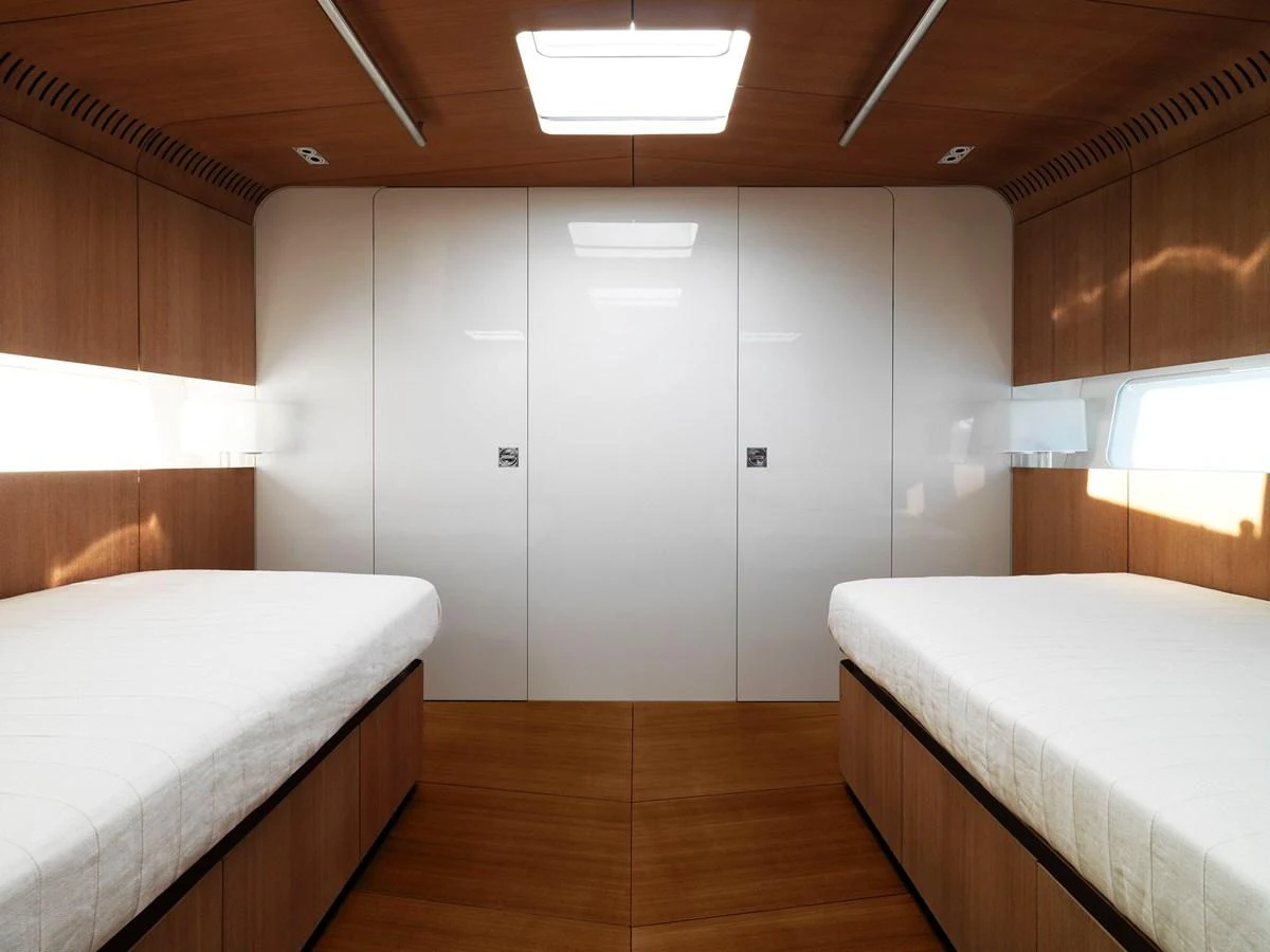 A modern twin stateroom with sleek wooden finishes and ample natural light. aboard S/Y SENTINEL Yacht for Sale