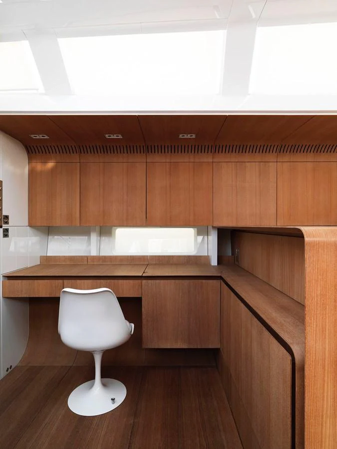 A sleek and modern workspace within the yacht, featuring wooden cabinetry and a stylish white chair. aboard S/Y SENTINEL Yacht for Sale