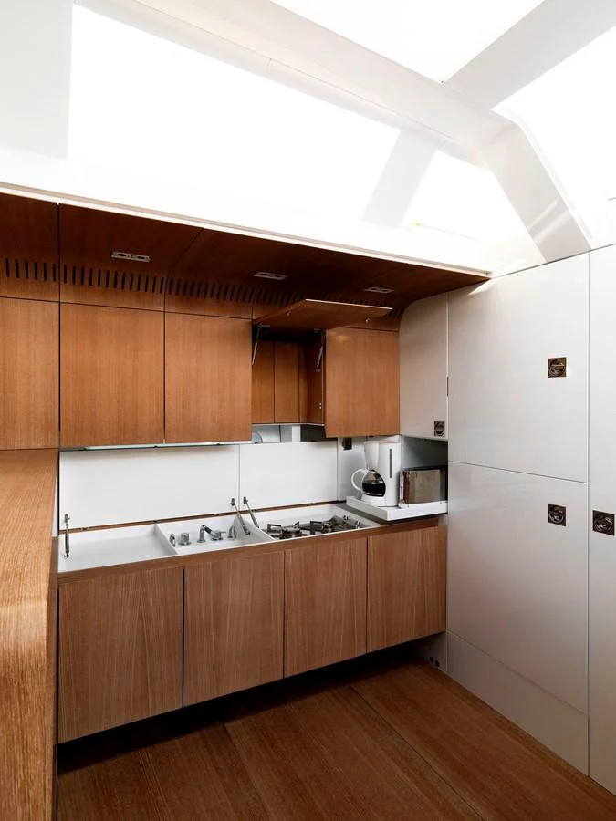The yacht's galley features modern wooden cabinetry and sleek appliances. aboard S/Y SENTINEL Yacht for Sale
