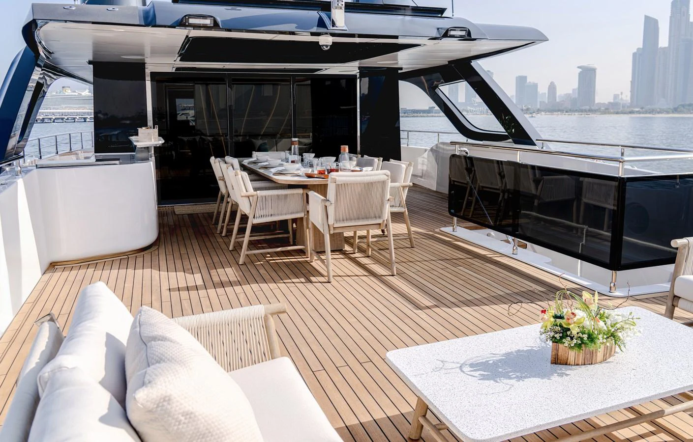 The aft deck features a spacious dining area with a stunning view of the city skyline. aboard MAJESTY 100 TERRACE Yacht for Sale