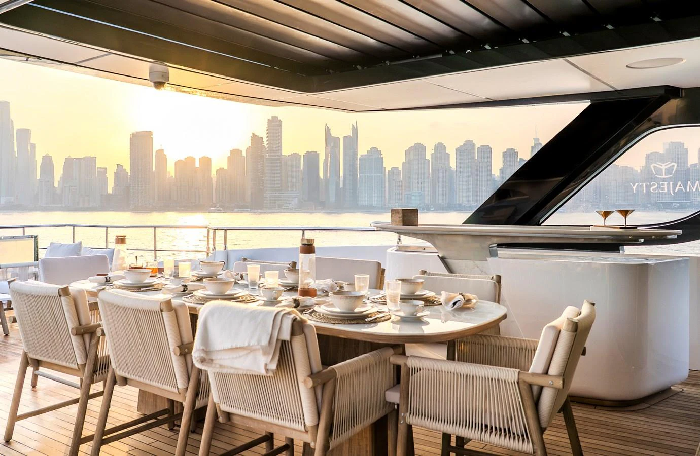 The aft deck offers a luxurious dining area with a stunning city skyline view. aboard MAJESTY 100 TERRACE Yacht for Sale