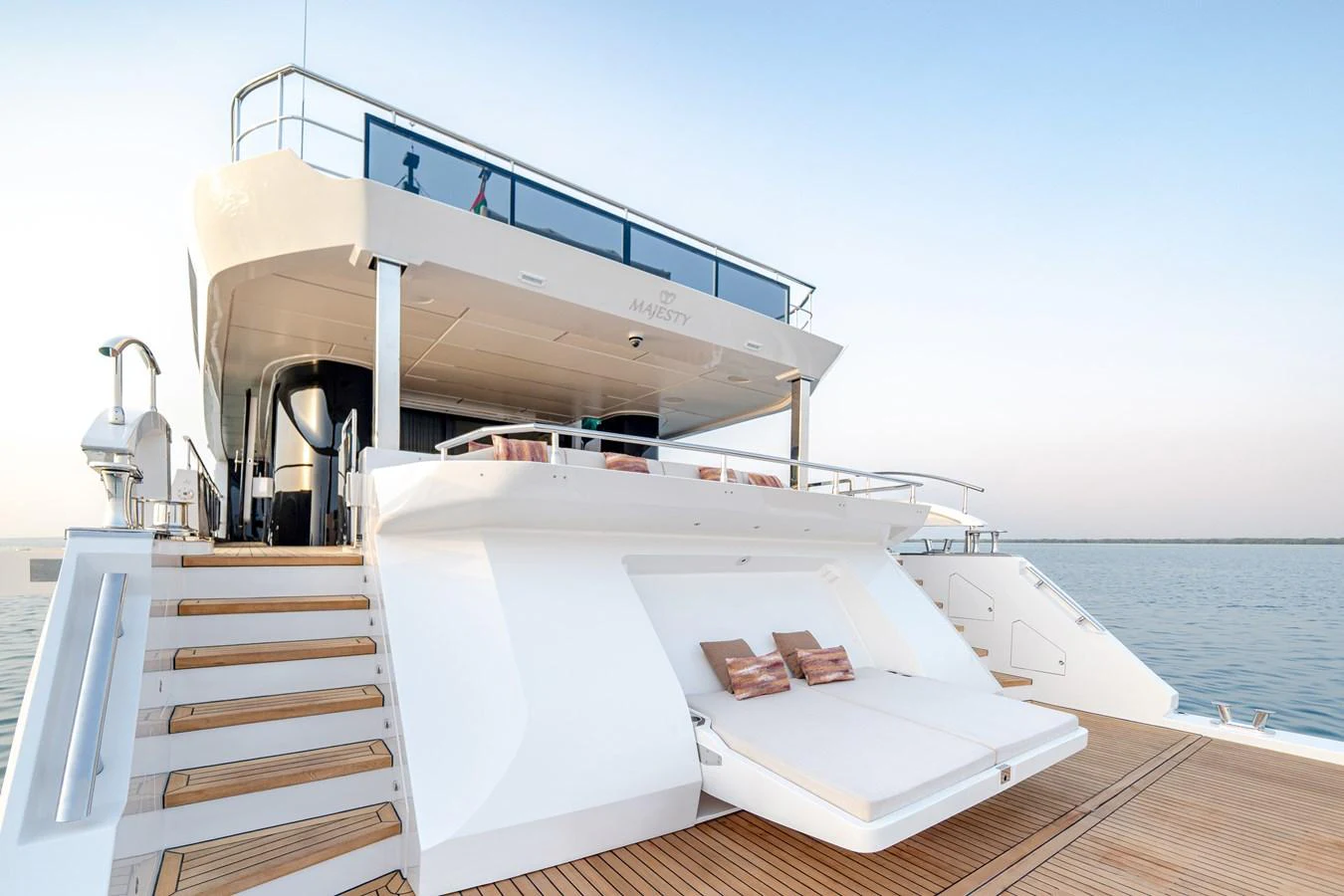 The yacht's aft deck features a spacious lounging area with sun pads and elegant wooden steps leading to the upper deck. aboard MAJESTY 100 TERRACE Yacht for Sale
