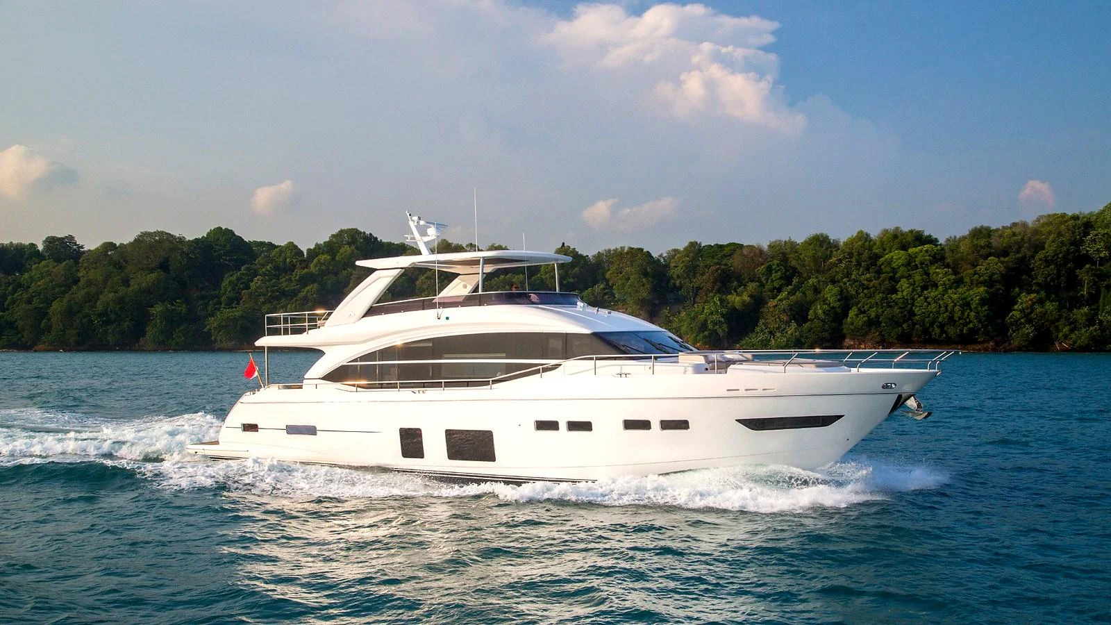 A sleek and modern yacht cruises gracefully on calm waters against a lush green backdrop. aboard PRINCESS CHLOE Yacht for Sale
