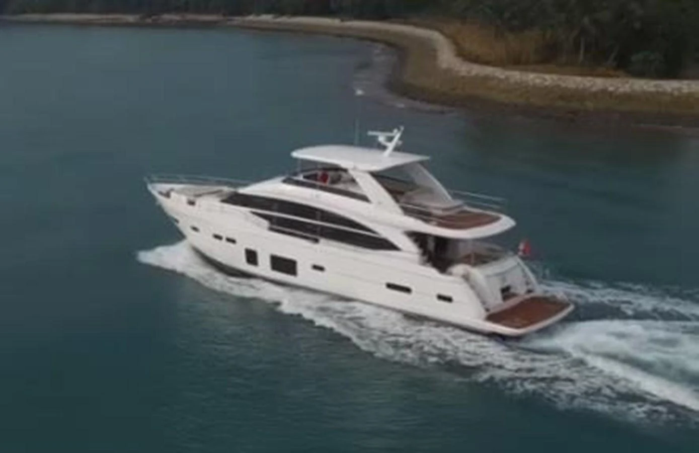 A sleek and modern yacht cruises along a serene coastline, showcasing its elegant design and spacious decks. aboard PRINCESS CHLOE Yacht for Sale
