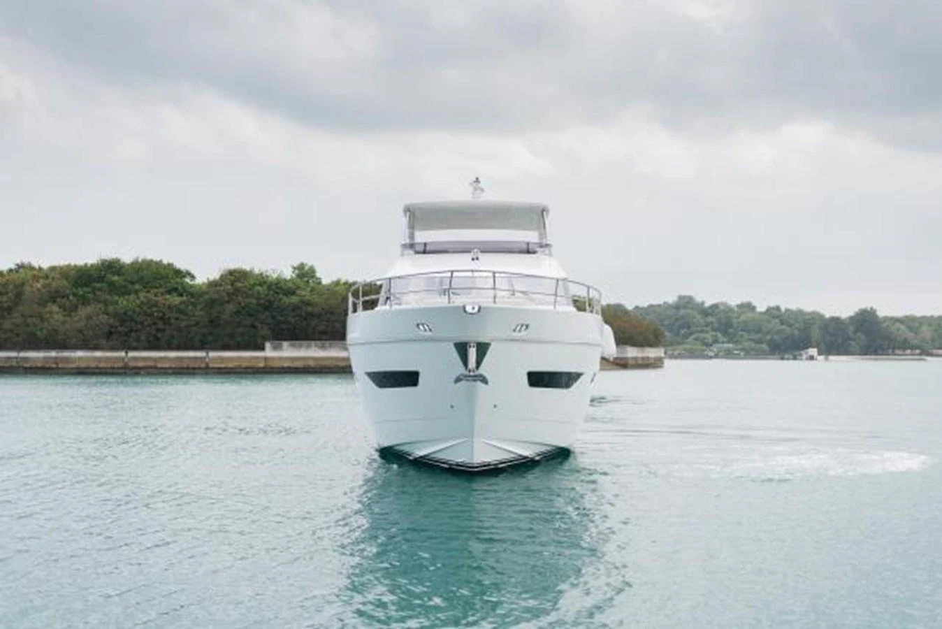 A sleek yacht is seen head-on, cruising on calm waters with a scenic backdrop. aboard PRINCESS CHLOE Yacht for Sale