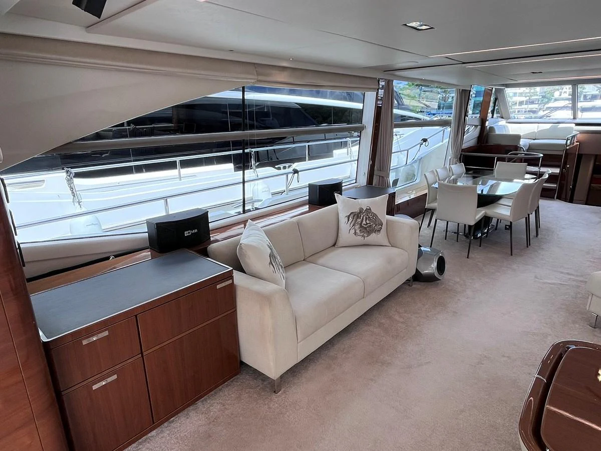 The salon features a comfortable seating area with a sofa and dining table, complemented by large windows offering a view of the exterior. aboard PRINCESS CHLOE Yacht for Sale