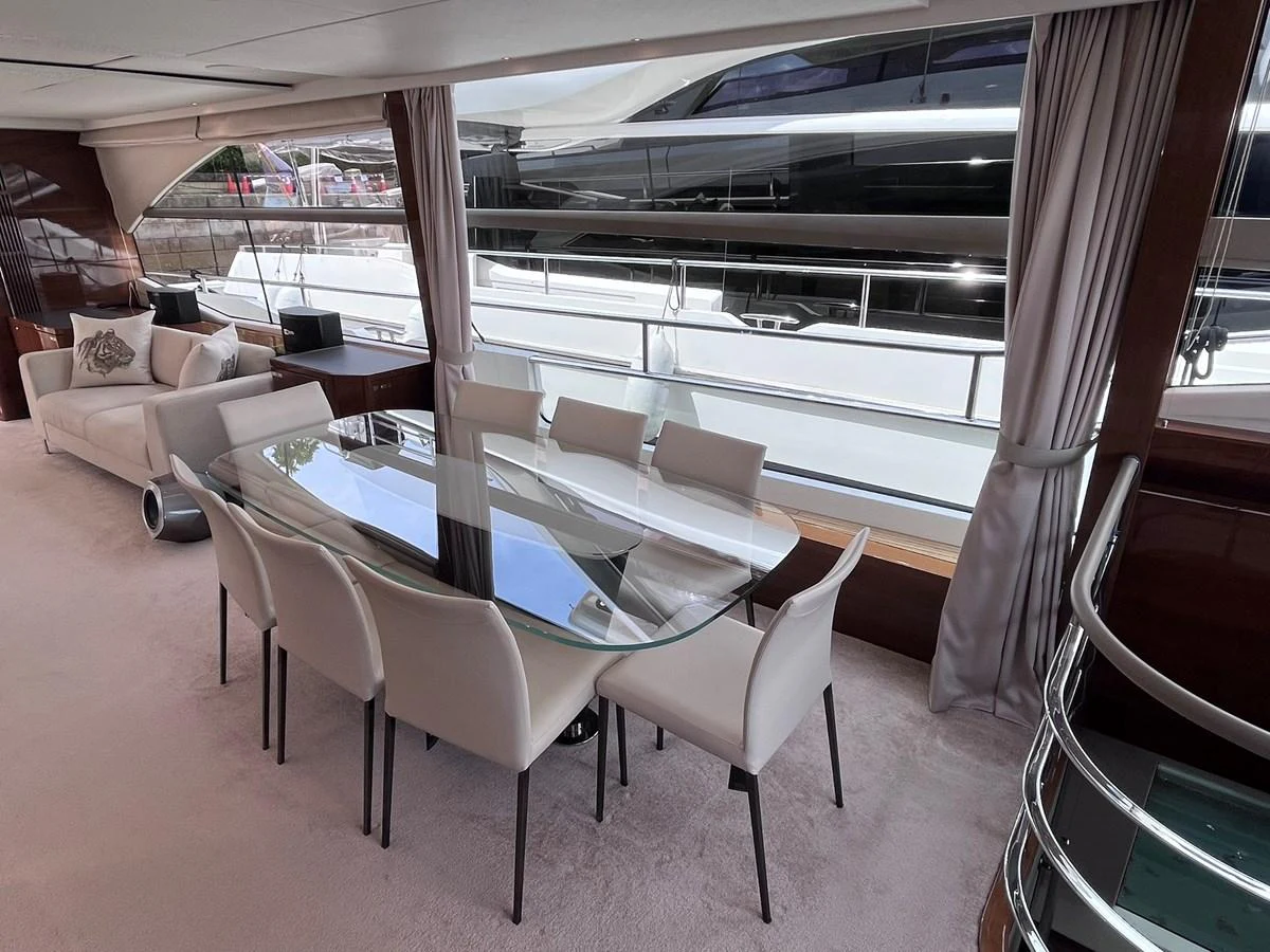 The yacht's dining area features a sleek glass table surrounded by modern white chairs, offering a stylish and comfortable space for meals. aboard PRINCESS CHLOE Yacht for Sale