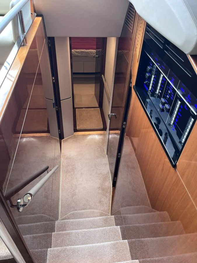 A luxurious staircase leads down to the lower deck, showcasing elegant wood paneling and modern design elements. aboard PRINCESS CHLOE Yacht for Sale