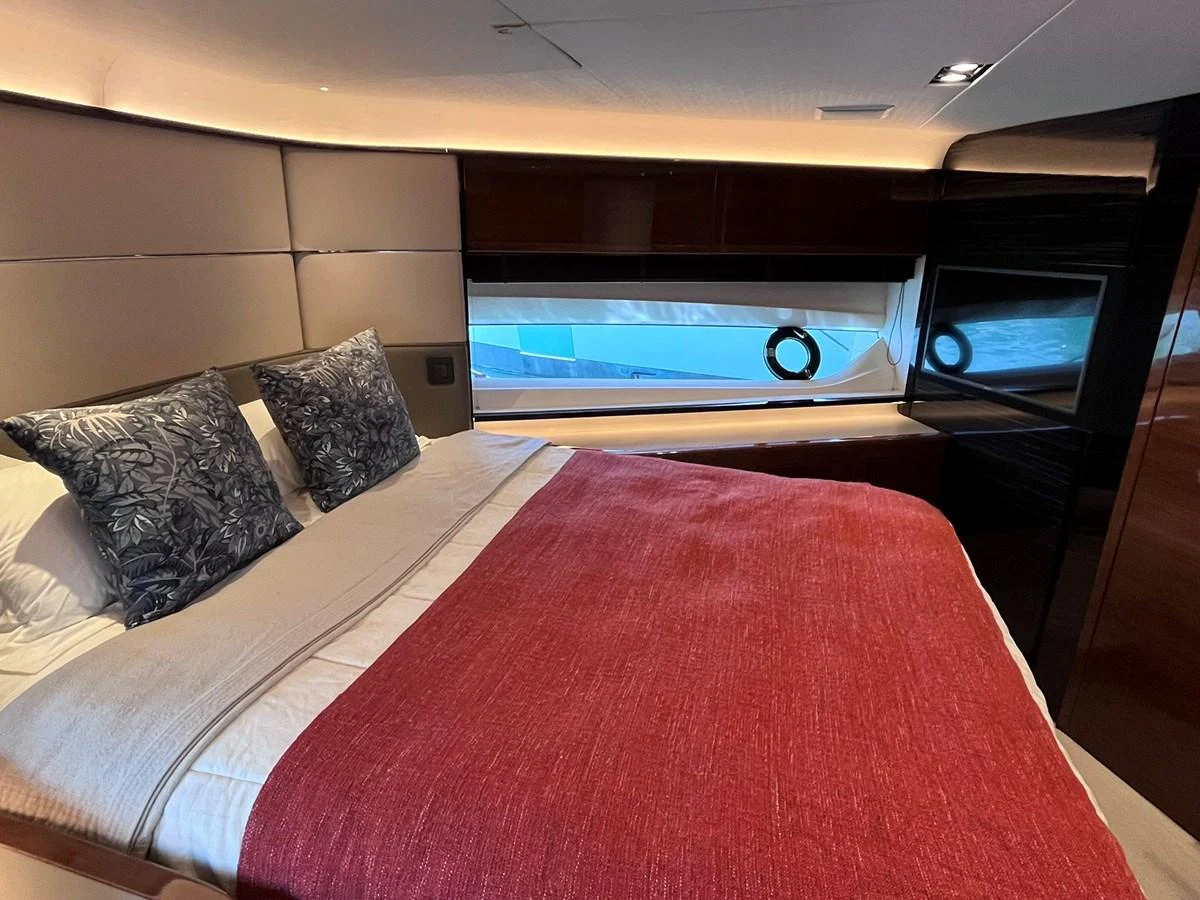 A cozy stateroom featuring a comfortable bed with plush pillows and a vibrant red blanket. aboard PRINCESS CHLOE Yacht for Sale