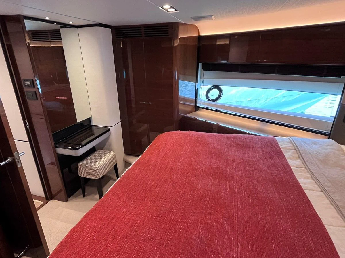 A cozy stateroom featuring a plush bed with a red cover and a small vanity area. aboard PRINCESS CHLOE Yacht for Sale