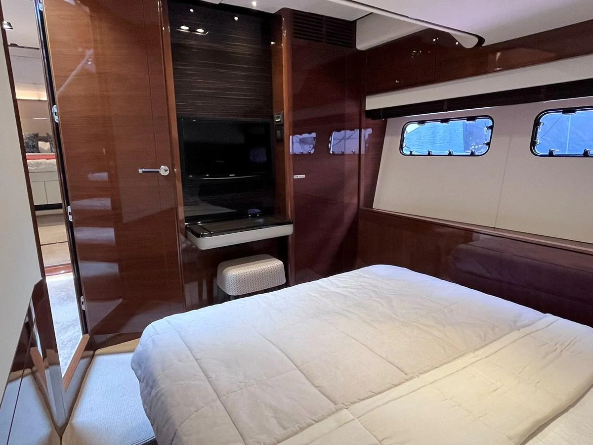 A cozy stateroom with a comfortable bed and a wall-mounted TV, featuring elegant wood paneling and ample natural light. aboard PRINCESS CHLOE Yacht for Sale