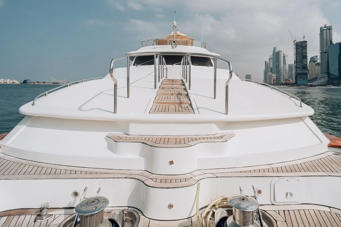 The foredeck of the yacht showcases a spacious and sleek design with a clear view of the city skyline in the background. aboard GALLUS Yacht for Sale