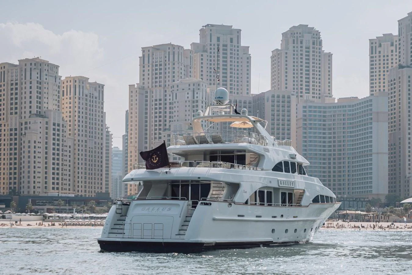 A luxurious yacht is anchored near a bustling cityscape with towering buildings in the background. aboard GALLUS Yacht for Sale