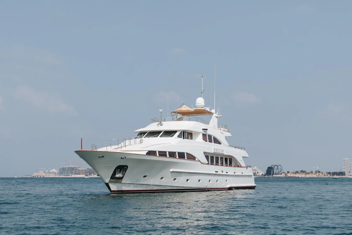 A luxurious yacht cruises gracefully on calm waters under a clear sky. aboard GALLUS Yacht for Sale