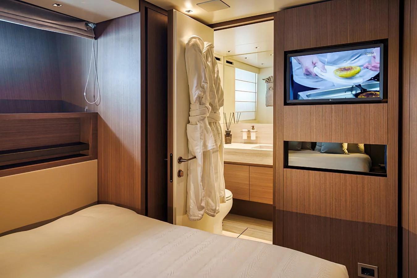 The cozy stateroom features a comfortable bed, a mounted TV, and an en-suite bathroom. aboard DESTINO Yacht for Sale