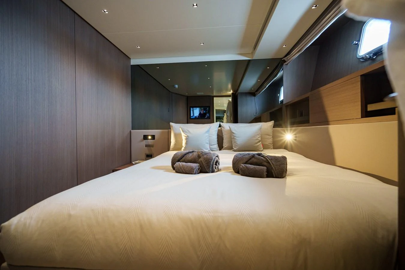 The stateroom features a plush bed with neatly arranged towels, creating a cozy and inviting atmosphere. aboard DESTINO Yacht for Sale
