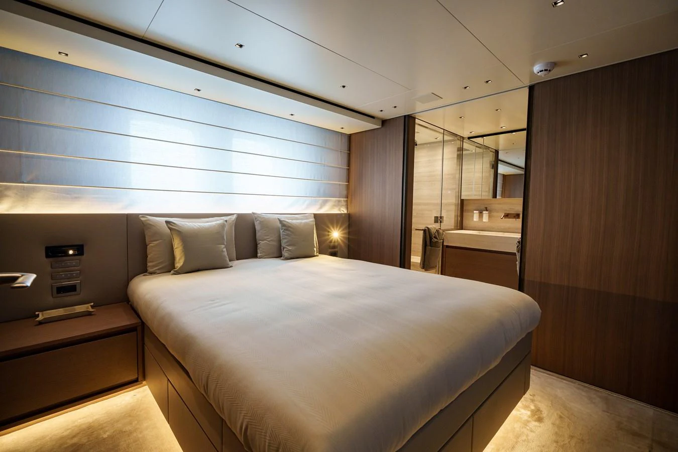 The master stateroom features a luxurious bed with modern lighting and elegant wood finishes. aboard DESTINO Yacht for Sale
