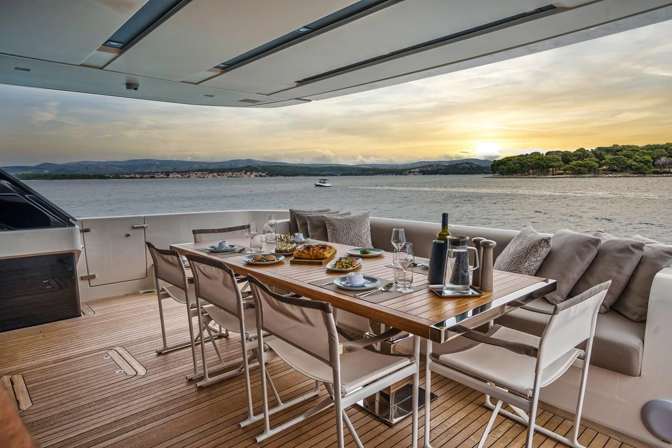 The aft deck features an elegant dining area with a stunning view of the sunset over the water. aboard DESTINO Yacht for Sale
