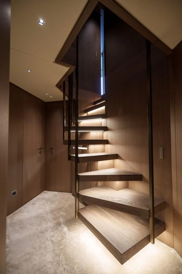 A modern staircase with sleek wooden steps and ambient lighting enhances the yacht's interior elegance. aboard DESTINO Yacht for Sale