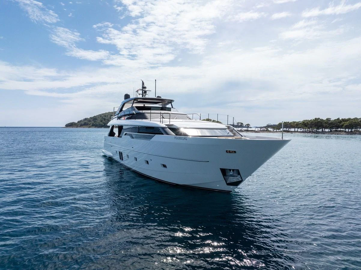 A sleek and modern yacht glides gracefully on calm waters under a partly cloudy sky. aboard DESTINO Yacht for Sale