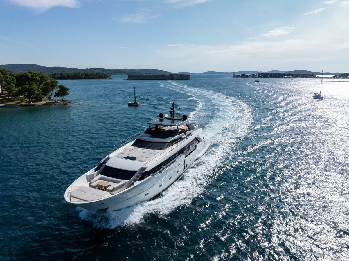 A sleek yacht cruises through clear blue waters, leaving a gentle wake behind. aboard DESTINO Yacht for Sale
