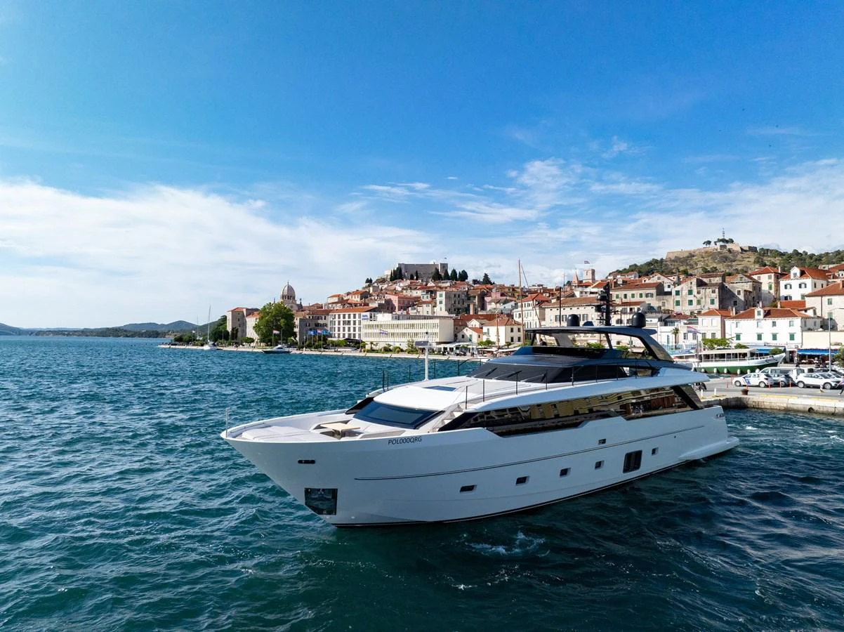 A sleek and modern yacht cruises gracefully near a picturesque coastal town. aboard DESTINO Yacht for Sale