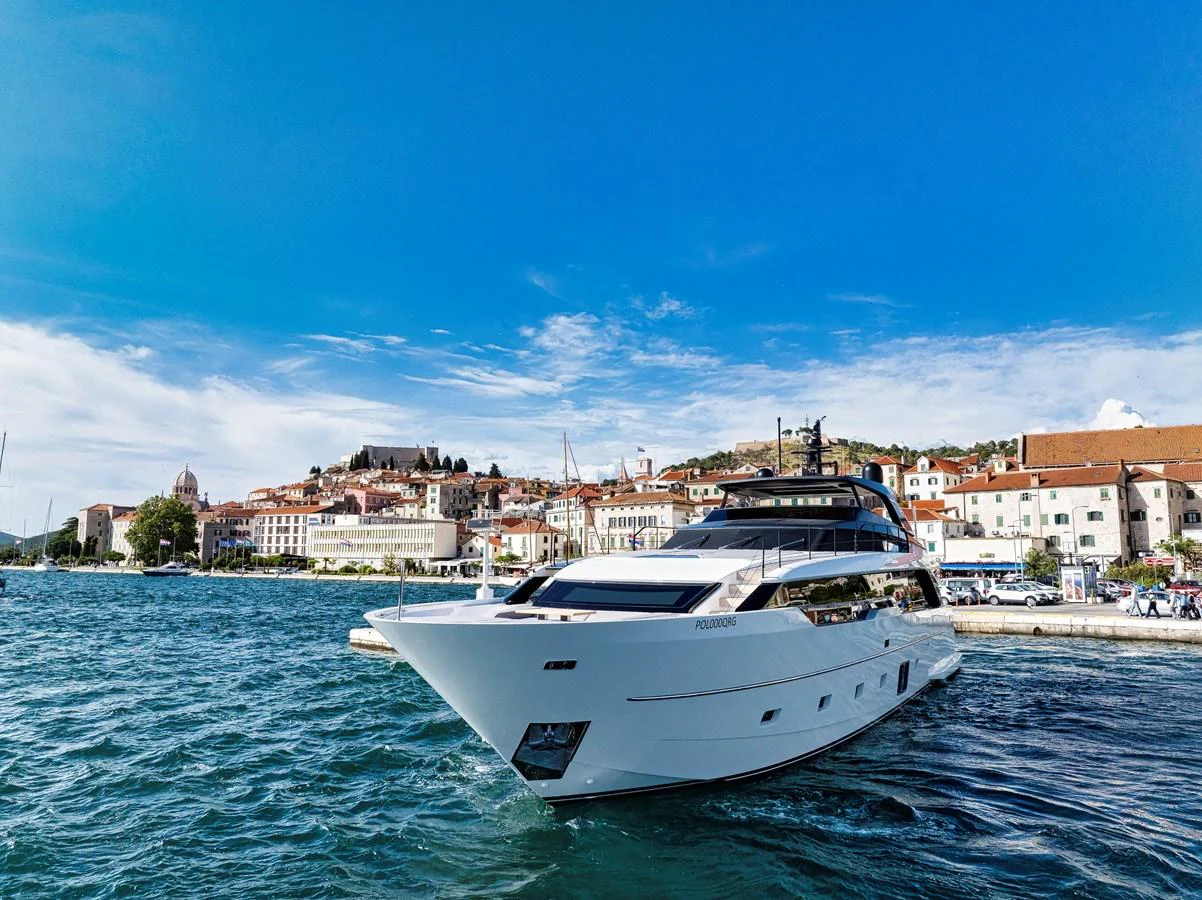 A sleek and modern yacht is docked in a picturesque harbor with a charming town in the background. aboard DESTINO Yacht for Sale