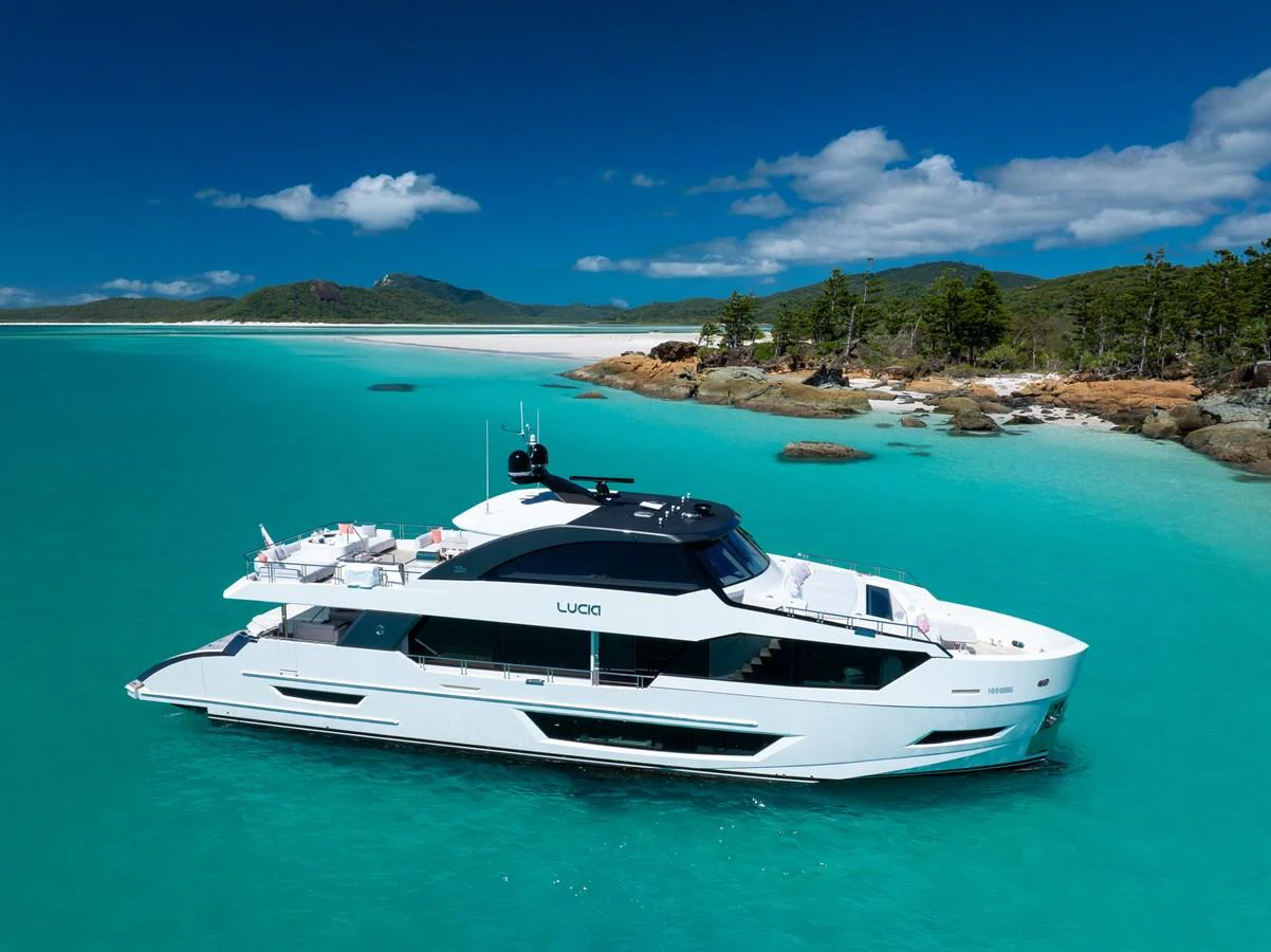 A sleek yacht cruises through pristine turquoise waters near a picturesque coastline. aboard G Yacht for Sale