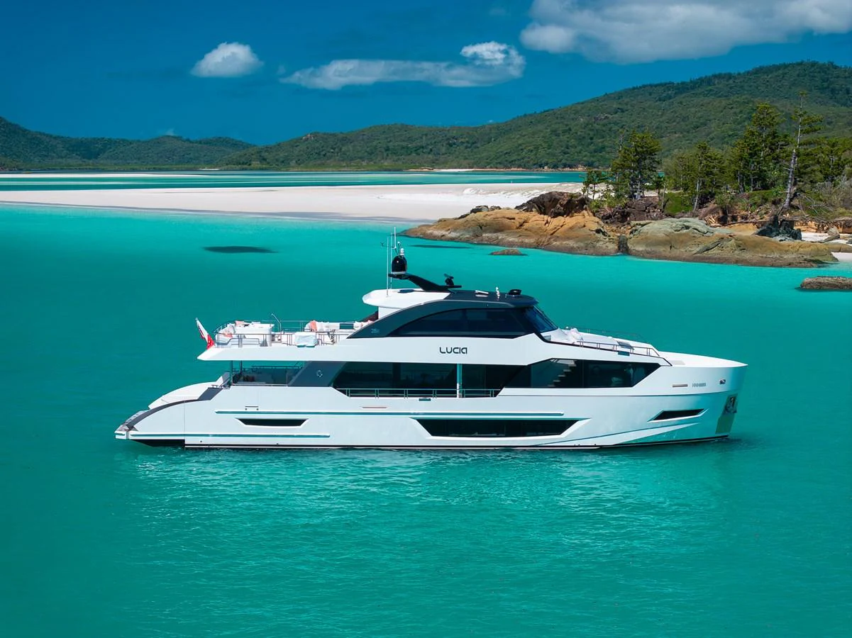 A sleek yacht cruises through turquoise waters near a picturesque coastline. aboard G Yacht for Sale