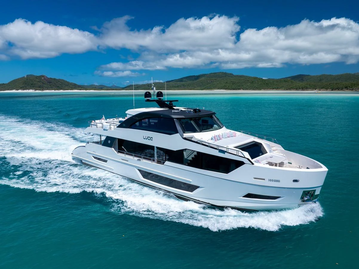 A sleek, modern yacht cruises through turquoise waters under a bright blue sky. aboard G Yacht for Sale