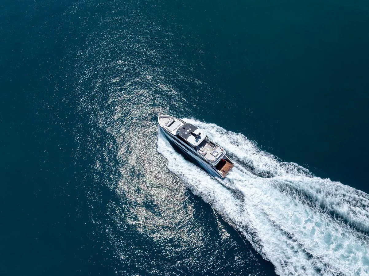 A sleek yacht cruises swiftly through the open water, leaving a trail of white wake behind. aboard G Yacht for Sale