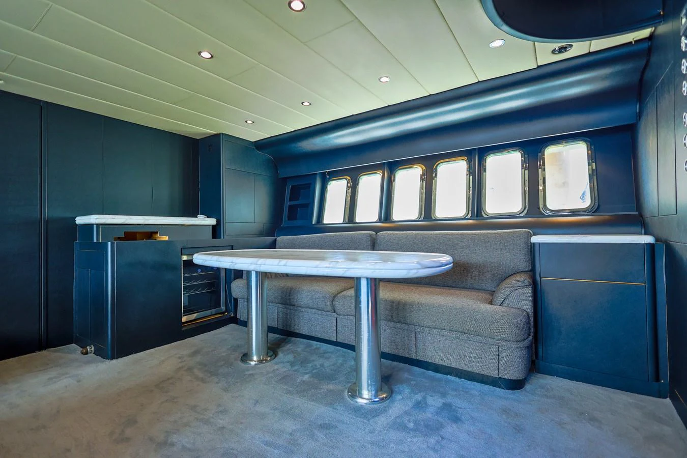 The yacht's interior features a sleek and modern seating area with a stylish table and ample natural light from large windows. aboard SEA SQUIRTER Yacht for Sale